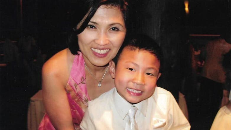Khue Pham, lead chef at Quang Restaurant, smiling and posing with her young son, Eric Pham, both dressed formally.